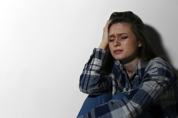 Κακοποιημένη νεαρή γυναίκα που κλαίει κοντά σε λευκό τοίχο, χώρος για κείμενο. Κτήματα - Φωτογραφία, εικόνα