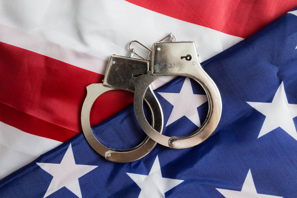 Handcuffs on the American flag, a concept of crime detection and crime rate in the United States - Photo, Image