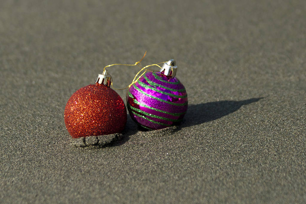 Zbliżenie dwóch kolorowych świątecznych kulek na piaszczystej plaży w świetle słonecznym - Zdjęcie, obraz