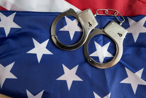 Handcuffs on the American flag, a concept of crime detection and crime rate in the United States - Foto, imagen