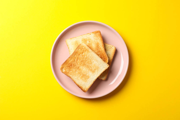 Plate with tasty toasts on yellow background, top view - Foto, Bild