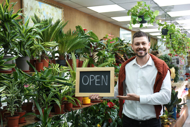 Male business owner holding OPEN sign in his flower shop - Φωτογραφία, εικόνα