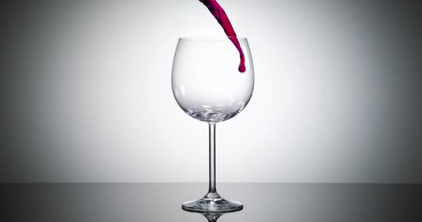 super zpomalený vysokorychlostní záběr červeného vína tekoucího do velkého bordeaux vinného skla - záběr ultra rychlostní kamerou - Záběry, video