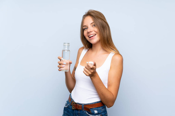 Young blonde girl with a bottle of water over isolated background - Foto, immagini