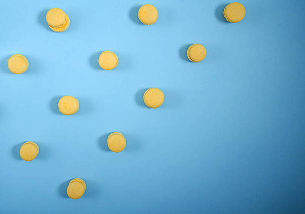 Yellow macarons lie in rows diagonally against a blue background - Foto, immagini