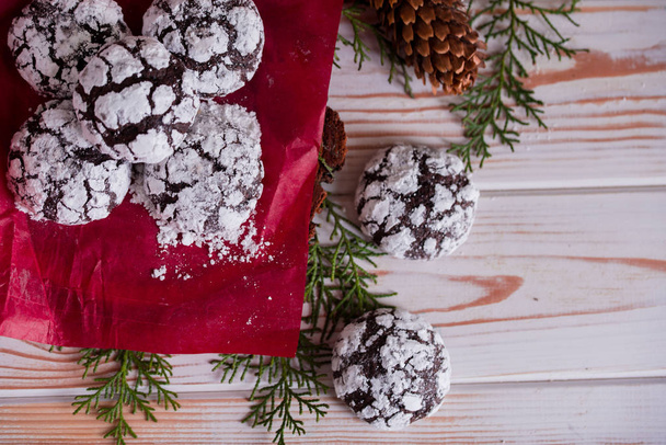 Вкусные и ароматные шоколадные печенья измельчаются с сахарной пудрой, с разноцветными огнями на столе. Счастливого Рождества!
 - Фото, изображение