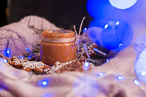 Νόστιμα και ευωδιαστά μπισκότα σοκολάτας συνθλίβονται με άχνη ζάχαρη, με πολύχρωμα φώτα στο τραπέζι. Καλά Χριστούγεννα. - Φωτογραφία, εικόνα
