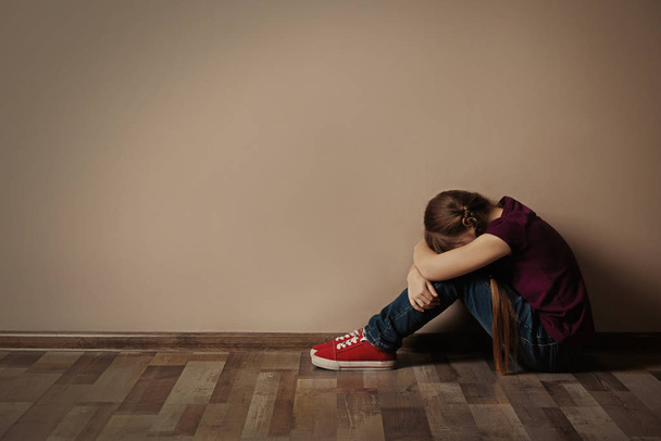Little girl on floor indoors, space for text. Child in danger - Valokuva, kuva