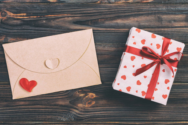 Obálky poštovní s červené srdce a dárkové krabice tmavé dřevěné pozadí. Valentine den karta, lásky nebo svatební pozdrav koncept - Fotografie, Obrázek