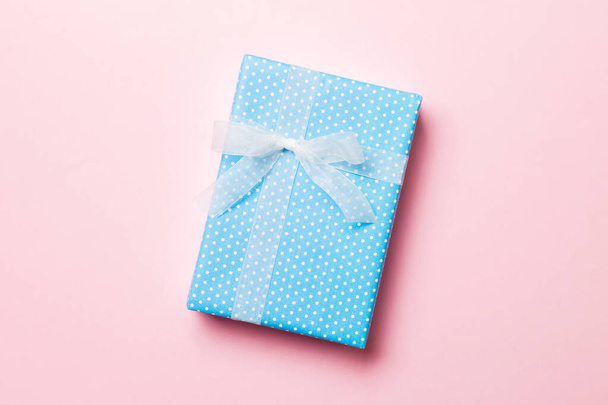 Gift box with white bow in hands for Christmas or New Year day on pink background, top view with copy space - Foto, Imagem