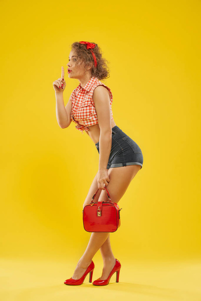 Stylish girl in red heel shoes with small red bag . - Foto, imagen