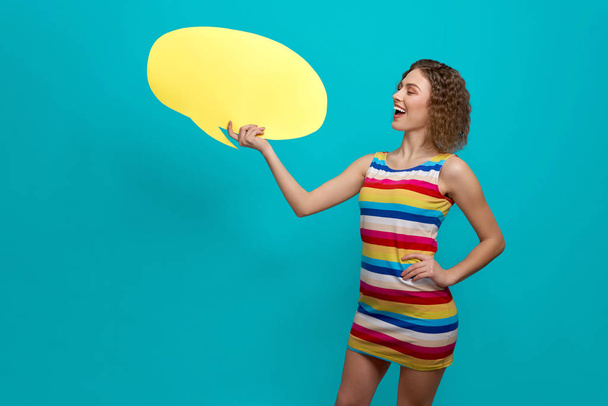 Girl holding and showing yellow speech bubble. - Foto, imagen