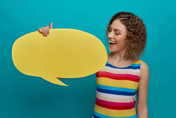 Smiling girl holding yellow paper speech bubble. - Photo, image