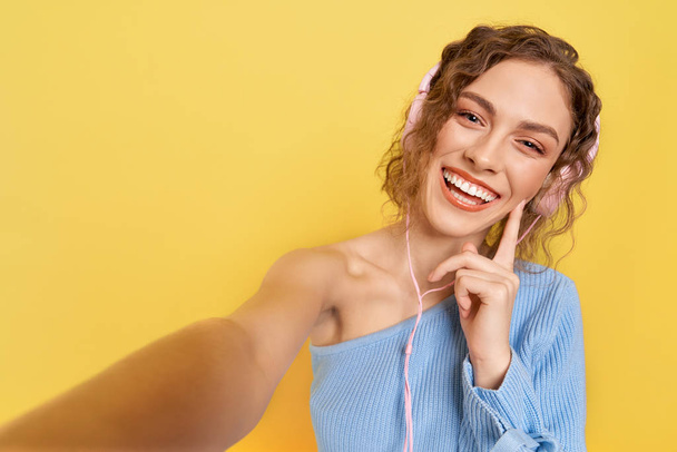 Cheerful model listening to music with headphones, smiling. - Fotó, kép