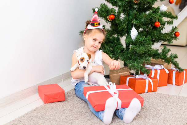 Ένα παιδί που ανοίγει χριστουγεννιάτικα δώρα. Παιδί κάτω από το χριστουγεννιάτικο δέντρο με κουτιά δώρων. - Φωτογραφία, εικόνα