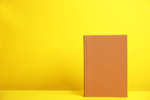 Hardcover book on yellow background. Space for design - Φωτογραφία, εικόνα