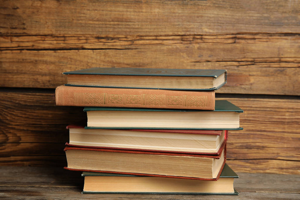 Collection of different books on table against wooden background - Фото, изображение