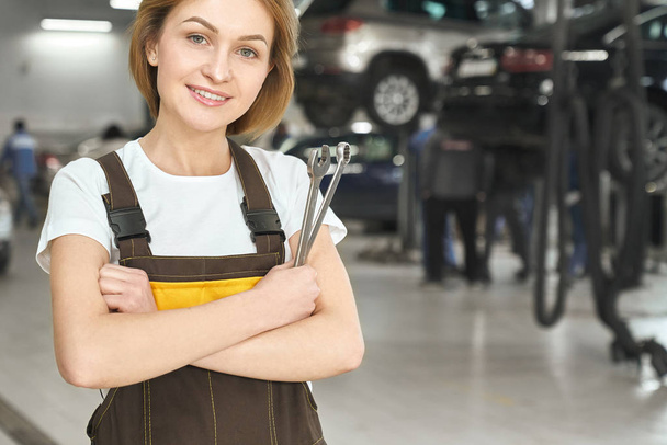 Professional female mechanic keeping wrench and posing - Photo, image