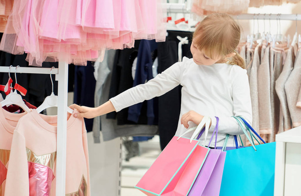 Cute girl holding bags and choosing pink sweater in store - Fotoğraf, Görsel