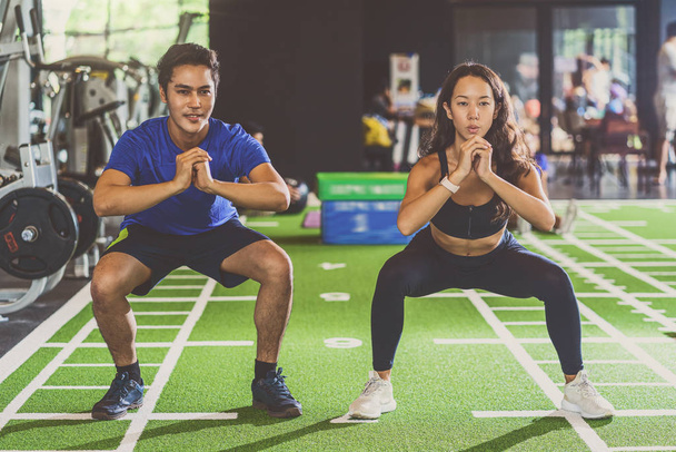 Couple young diversity working out in gym fitness sport complex, doing squad and cardio, posture position, Push up on weights, sports and healthcare,asian and asean people, concept - Photo, Image