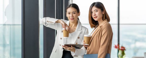 Banner, webpagina of omslag sjabloon van Twee Aziatische zakenvrouwen praten tijdens koffiepauze in modern kantoor of coworking ruimte, koffiepauze, ontspannen en praten, business en mensen partnerschap concept - Foto, afbeelding