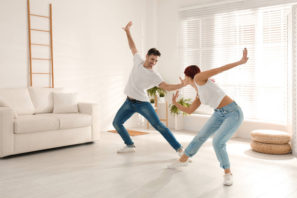 Beautiful young couple dancing in living room - Фото, зображення