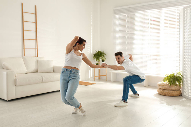 Beautiful young couple dancing in living room - Фото, изображение
