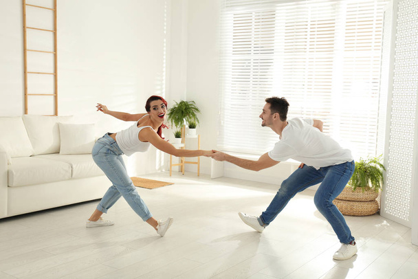 Beautiful young couple dancing in living room - Fotó, kép