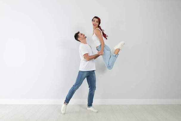Красива молода пара танцює біля світлої стіни
 - Фото, зображення