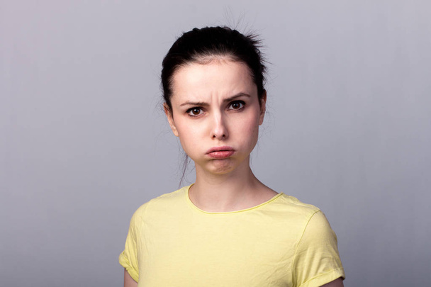 young emotional girl in a yellow t-shirt on a gray background - Fotografie, Obrázek