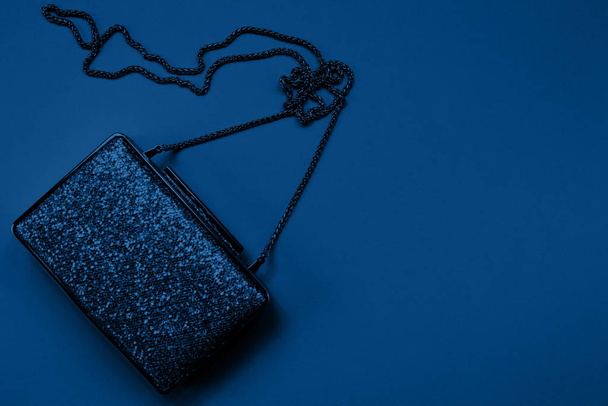 Festive evening golden clutch on classic blue. Holiday and celebration background. Luxury accessories and party concept - Photo, Image