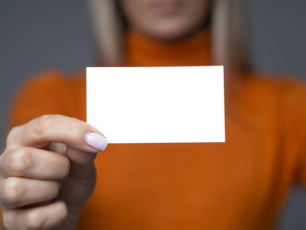 Mockup tarjeta de visita en blanco en manos femeninas con enfoque selectivo en una tarjeta, fondo gris oscuro
 - Foto, Imagen