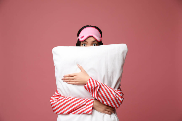 Beautiful Asian woman with pillow on dusty rose background. Bedt - Foto, imagen