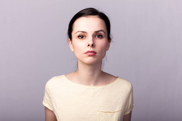 young emotional girl in a yellow t-shirt on a gray background - Foto, Imagem