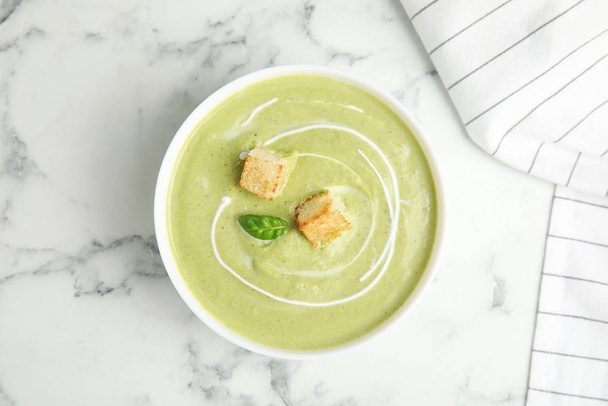 Delicious broccoli cream soup with croutons served on white marble table, top view - Foto, Bild