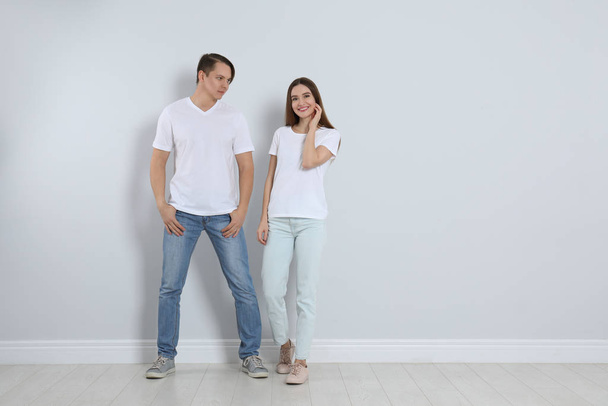 Молодая пара в стильных джинсах возле светлой стены
 - Фото, изображение