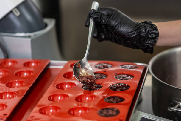 Confectioner in gloves makes chocolates in forms - Φωτογραφία, εικόνα
