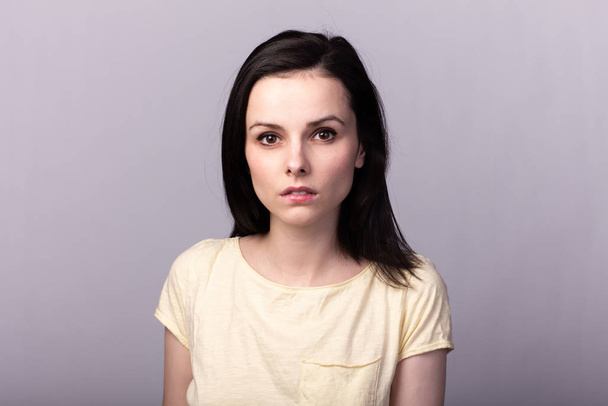 young emotional girl in a yellow t-shirt on a gray background - Fotoğraf, Görsel