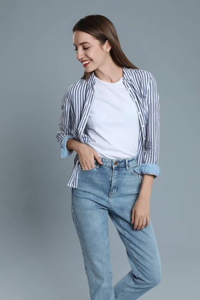 Young woman in stylish jeans on grey background - Foto, afbeelding