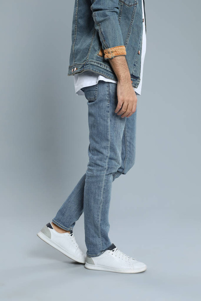 Young man in stylish jeans on grey background, closeup - Foto, Imagen