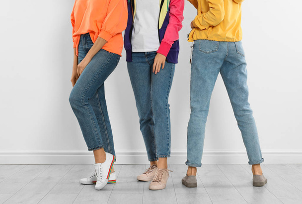Group of young women in stylish jeans near white wall, closeup - Фото, зображення