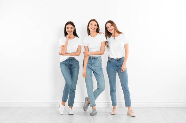 Group of young women in stylish jeans near white wall - Zdjęcie, obraz