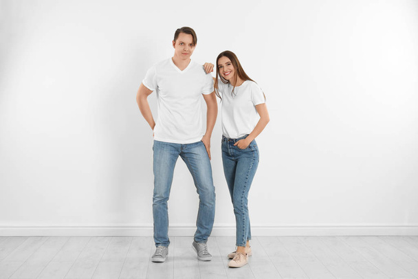 Young couple in stylish jeans near white wall - Valokuva, kuva