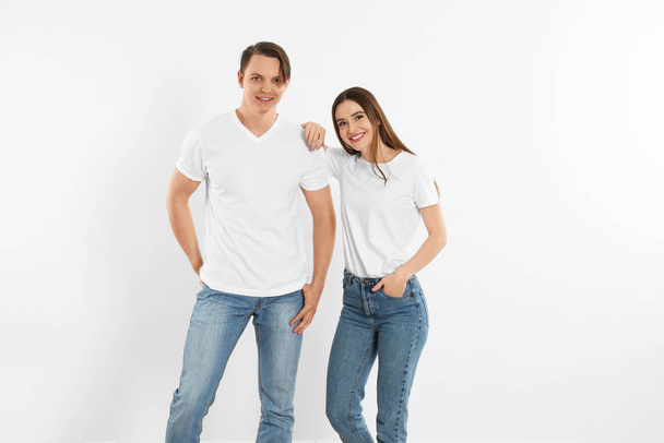 Young couple in stylish jeans near white wall - Valokuva, kuva