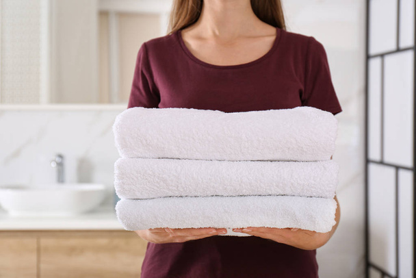 Woman holding fresh towels in bathroom, closeup - Fotoğraf, Görsel