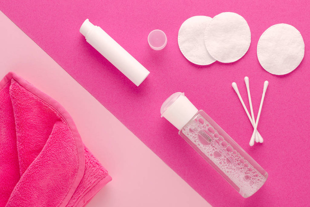 démaquiller les produits, eau micellaire, lingette nettoyante pour le visage, lait nettoyant et tampons de coton sur fond rose
 - Photo, image