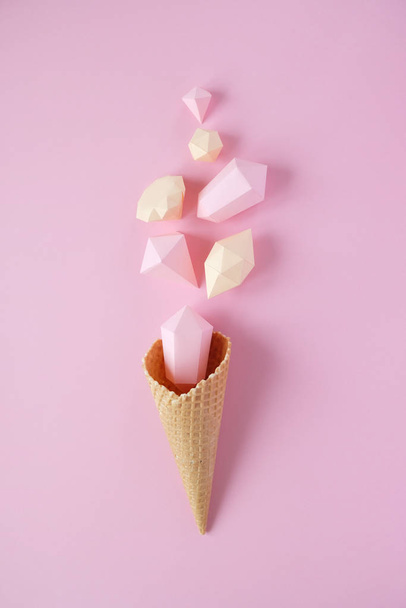 Hand holds a waffle cone with paper diamonds on pink background. Holiday concept. - Photo, image