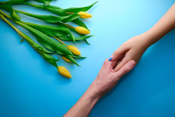 Tenant la main sur fond bleu avec tulipes, vue de dessus, concept vacances
 - Photo, image