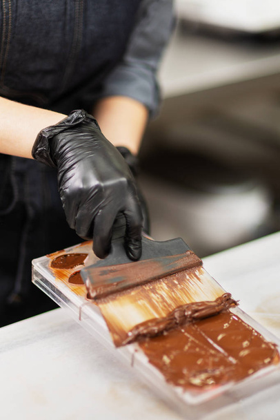 Confectioner in gloves makes chocolates in forms - Zdjęcie, obraz