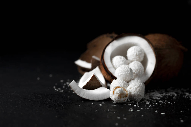 cooked coconut milk candies on a black dark background, ingredients for a dessert with coconuts, a sweet product with coconut flakes - Photo, image